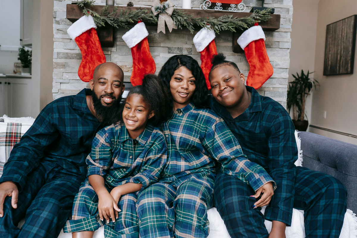 Happy black family in pajamas on couch during Christmas holidays